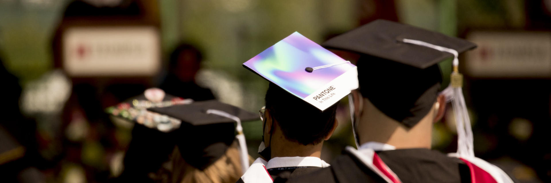 An image of Students facing the stage at commencement dressed in their caps and gowns.