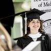 An image of a smiling graduated student on stage at commencement. 