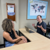 A student talks with a peer advisor over an L-shaped wooden desk